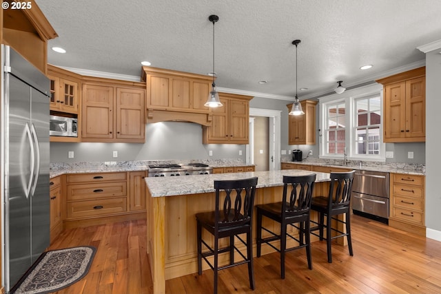 kitchen with appliances with stainless steel finishes, pendant lighting, a kitchen island, and a kitchen breakfast bar