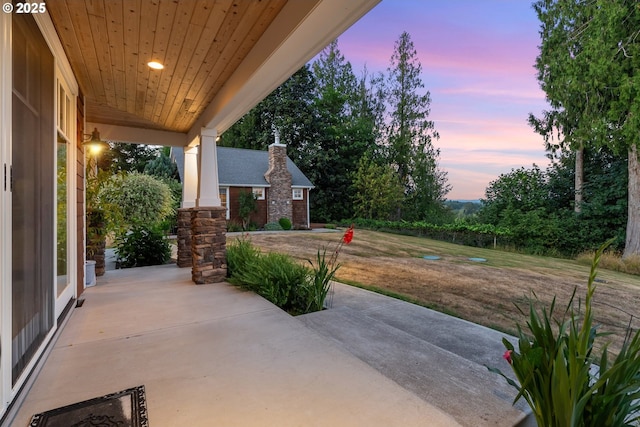 patio terrace at dusk featuring a lawn