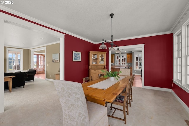 dining area with french doors, light colored carpet, a textured ceiling, and ornamental molding