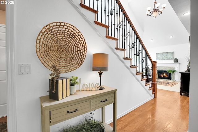 12909 SW Jacob Ct, Portland, OR 97224 - stairway with wood finished floors, a chandelier, a lit fireplace, and recessed lighting