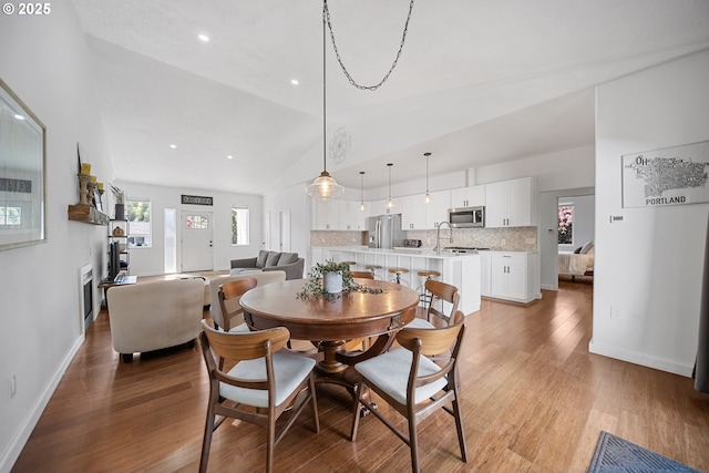 dining area featuring baseboards, recessed lighting, light wood-style flooring, and high vaulted ceiling