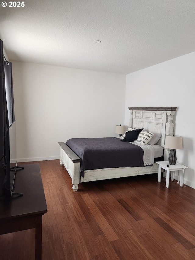 bedroom featuring a textured ceiling, baseboards, and wood finished floors