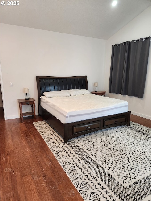 bedroom featuring baseboards, wood finished floors, and lofted ceiling