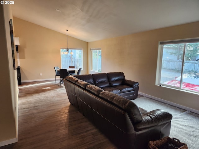 living area featuring baseboards, an inviting chandelier, dark wood-style floors, and lofted ceiling