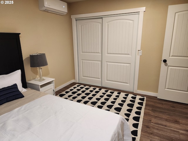 bedroom with an AC wall unit, baseboards, dark wood-style floors, and a closet
