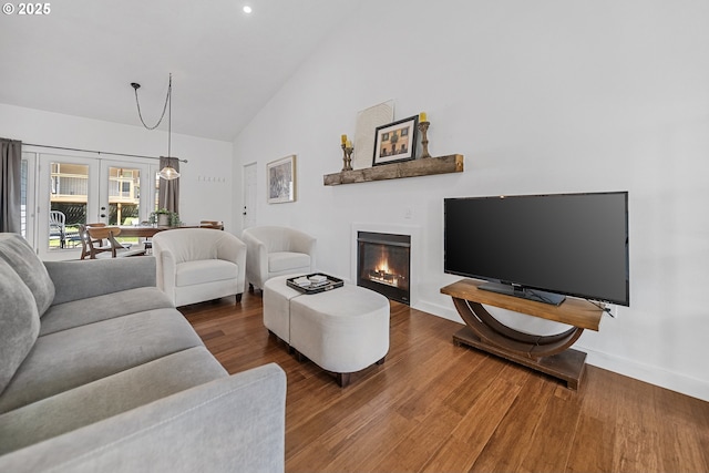 living area with wood finished floors, high vaulted ceiling, baseboards, a glass covered fireplace, and recessed lighting