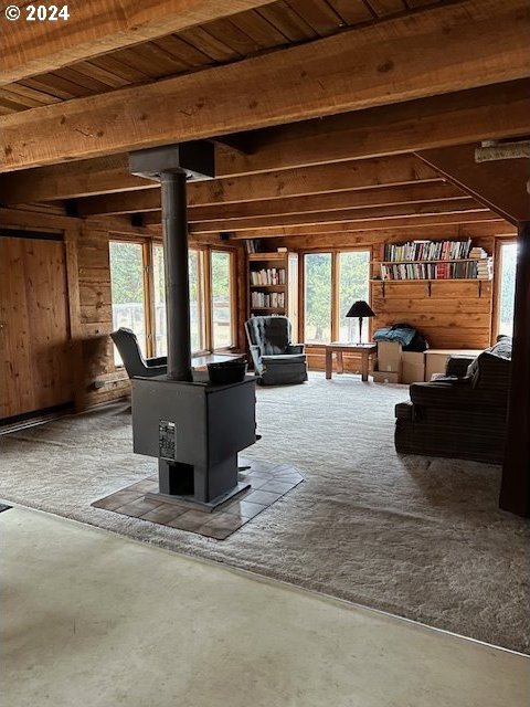 60327 Lower Divide Rd, Joseph, OR 97846 - living room featuring a wood stove, wooden walls, healthy amount of natural light, and wooden ceiling with exposed beams