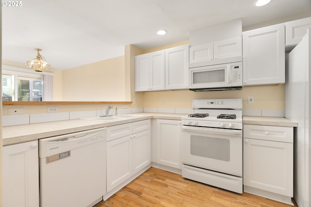 kitchen featuring sink, pendant lighting, white cabinets, and white appliances