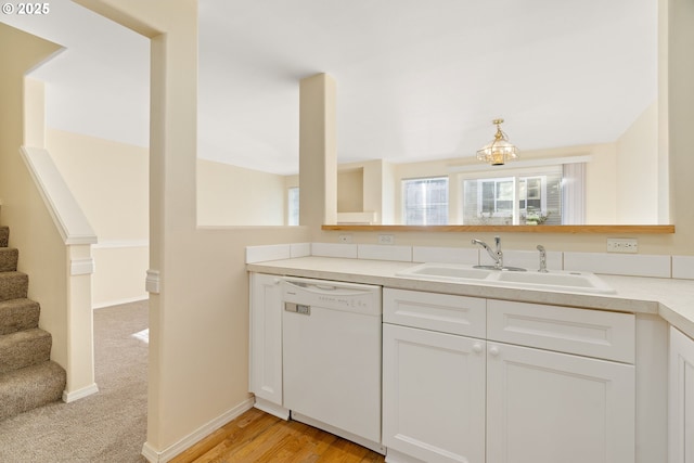 kitchen featuring white dishwasher, sink, white cabinetry, and light colored carpet