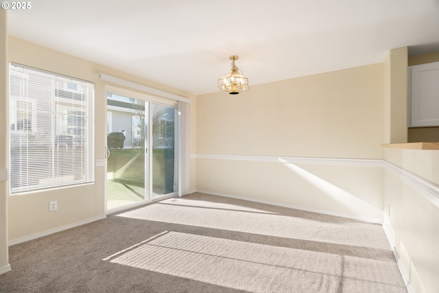 carpeted empty room featuring a chandelier