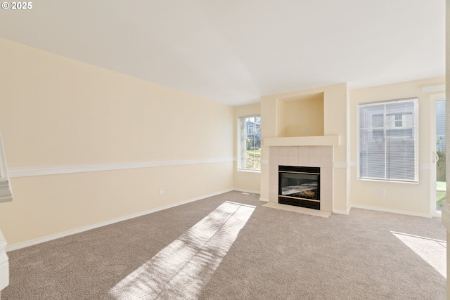 unfurnished living room with light colored carpet and a tiled fireplace