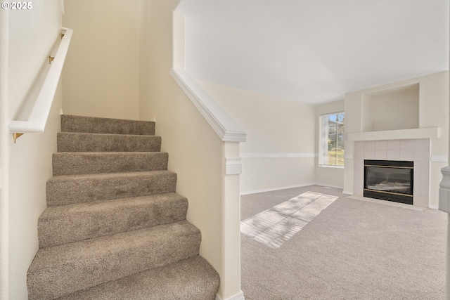 staircase with carpet flooring and a tile fireplace