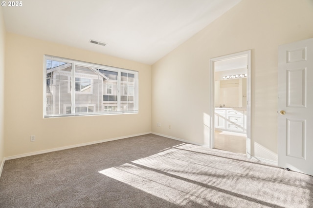 unfurnished bedroom featuring ensuite bath, lofted ceiling, carpet floors, and multiple windows