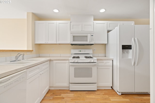 kitchen with white cabinetry, sink, white appliances, and light hardwood / wood-style flooring