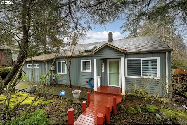 view of front of home with board and batten siding, roof with shingles, and a chimney