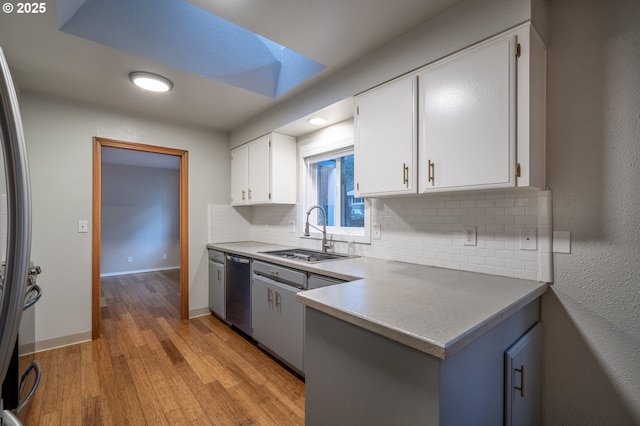 kitchen featuring light countertops, appliances with stainless steel finishes, a sink, and white cabinets