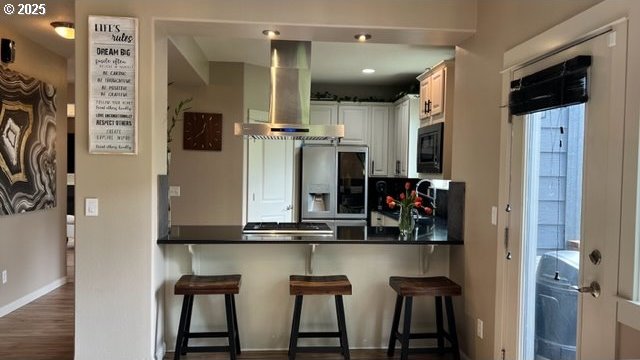 kitchen with stainless steel fridge with ice dispenser, black microwave, ventilation hood, baseboards, and a peninsula