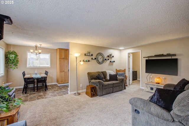 living area with light carpet, a notable chandelier, a textured ceiling, and baseboards