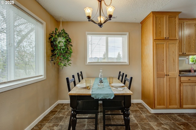 dining room featuring dark tile patterned flooring, baseboards, a chandelier, and a textured ceiling