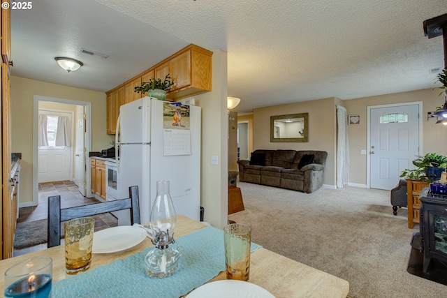 dining space with visible vents, a textured ceiling, carpet floors, baseboards, and a wood stove