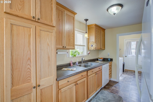 kitchen featuring dark countertops, baseboards, hanging light fixtures, white appliances, and a sink