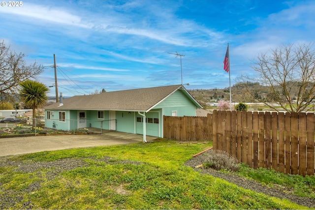 view of front facade with a front yard, driveway, and fence