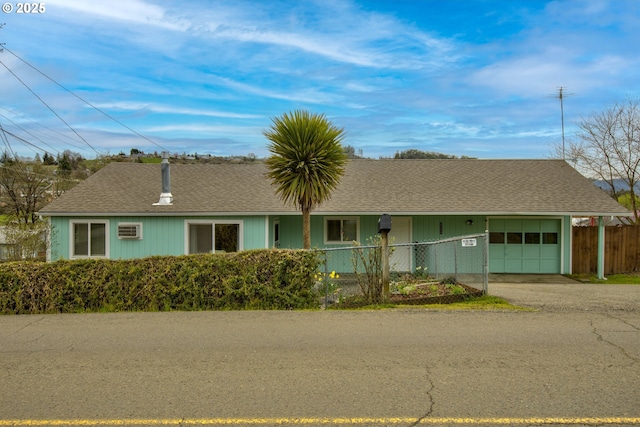 ranch-style house featuring aphalt driveway, roof with shingles, an attached garage, and fence