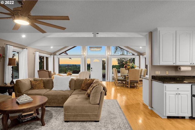 living room with light hardwood / wood-style flooring, ceiling fan, and lofted ceiling with beams