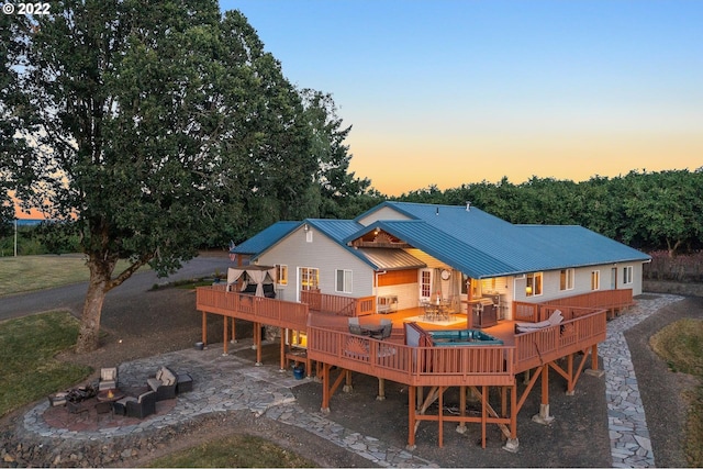 back house at dusk featuring a deck and a patio