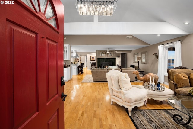 living room with an inviting chandelier, vaulted ceiling, and light wood-type flooring