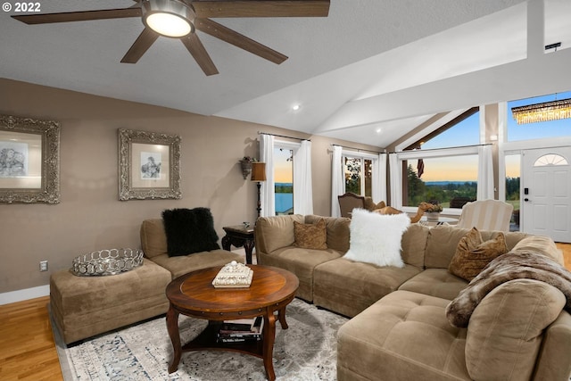 living room with light hardwood / wood-style floors, ceiling fan, and vaulted ceiling