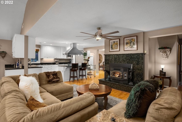 living room featuring a textured ceiling, light hardwood / wood-style floors, ceiling fan, and a premium fireplace