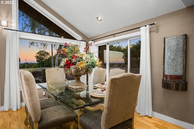 dining space with vaulted ceiling and light wood-type flooring