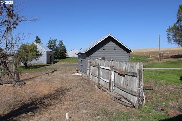view of home's exterior with fence and a rural view