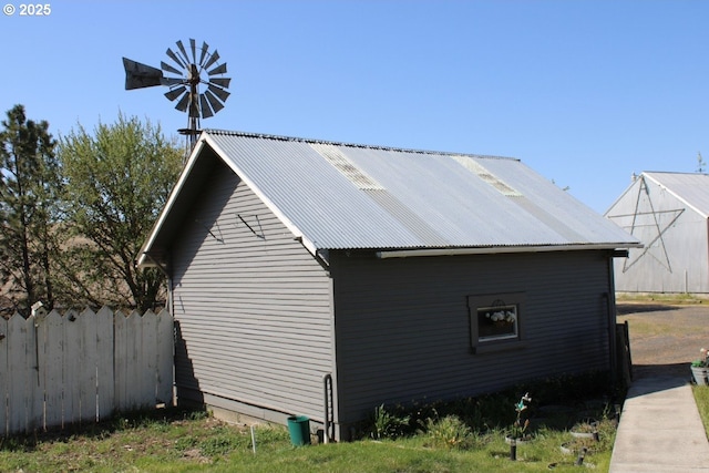 view of side of home with fence and metal roof