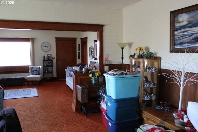 carpeted living area featuring ornamental molding, wainscoting, and wallpapered walls