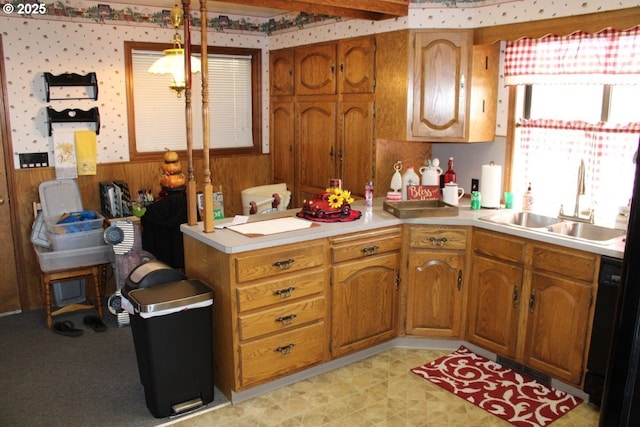 kitchen featuring light countertops, a peninsula, brown cabinets, and a sink