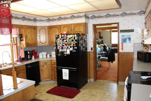 kitchen with brown cabinetry, a sink, black appliances, and light countertops