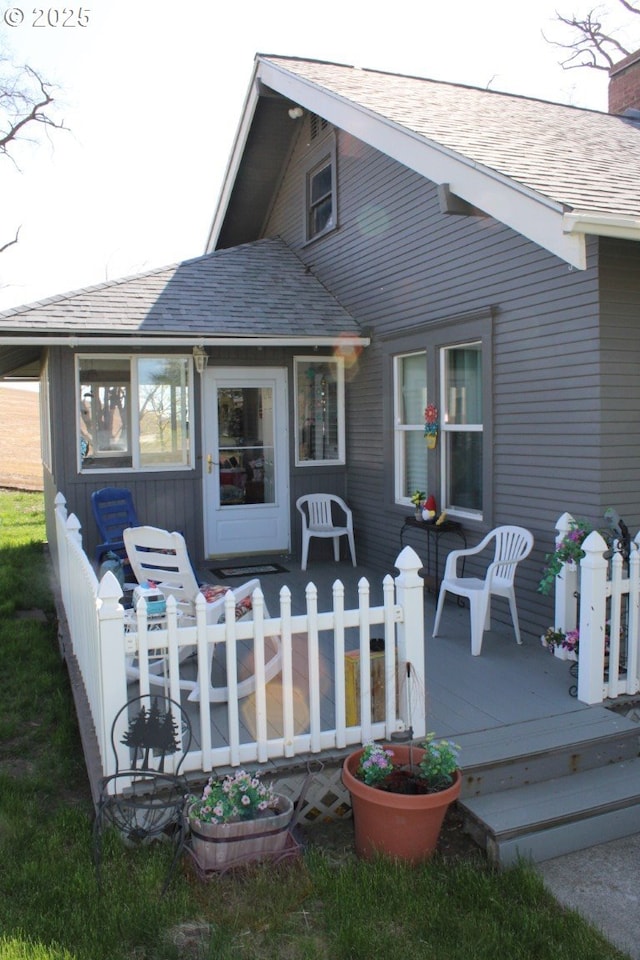 back of house featuring a wooden deck and roof with shingles