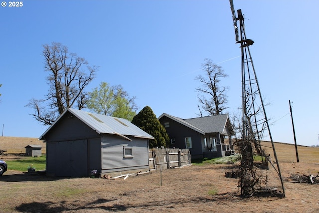 view of property exterior featuring fence, an outbuilding, and a shed