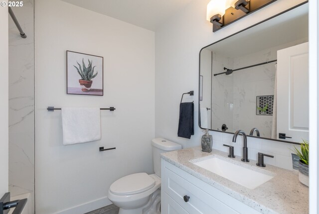 bathroom featuring toilet, tiled shower, decorative backsplash, and vanity