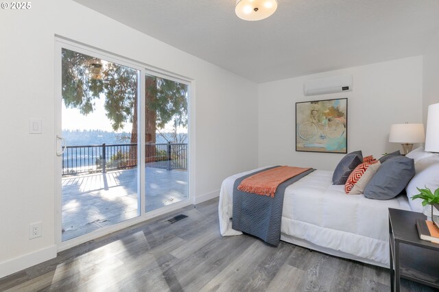 bedroom with access to exterior, hardwood / wood-style floors, and a wall mounted air conditioner