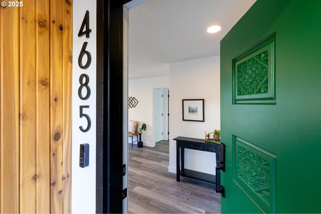 hallway with a textured ceiling and wood-type flooring