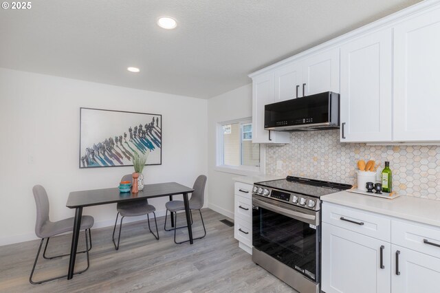 kitchen featuring tasteful backsplash, white cabinets, light wood-type flooring, and stainless steel range with electric stovetop