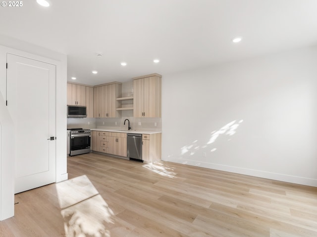 kitchen with light countertops, decorative backsplash, stainless steel appliances, light wood finished floors, and light brown cabinetry