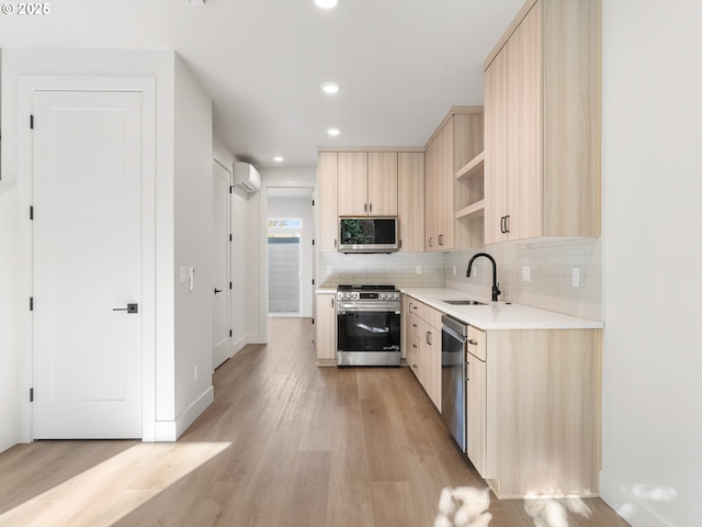 kitchen with light brown cabinets, a wall mounted air conditioner, a sink, light countertops, and stainless steel appliances