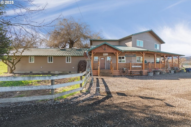 view of front of house featuring covered porch, fence, and metal roof