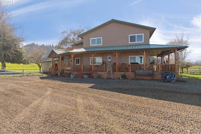 view of front of home with a porch, metal roof, and fence