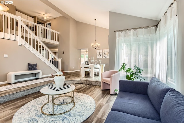 living room featuring a chandelier, stairway, high vaulted ceiling, and wood finished floors