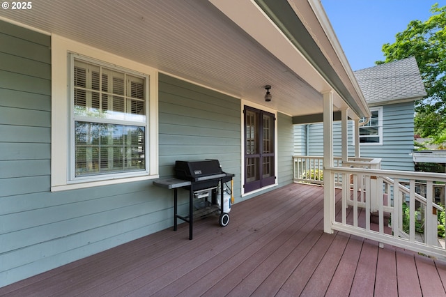 wooden deck featuring a porch and a grill